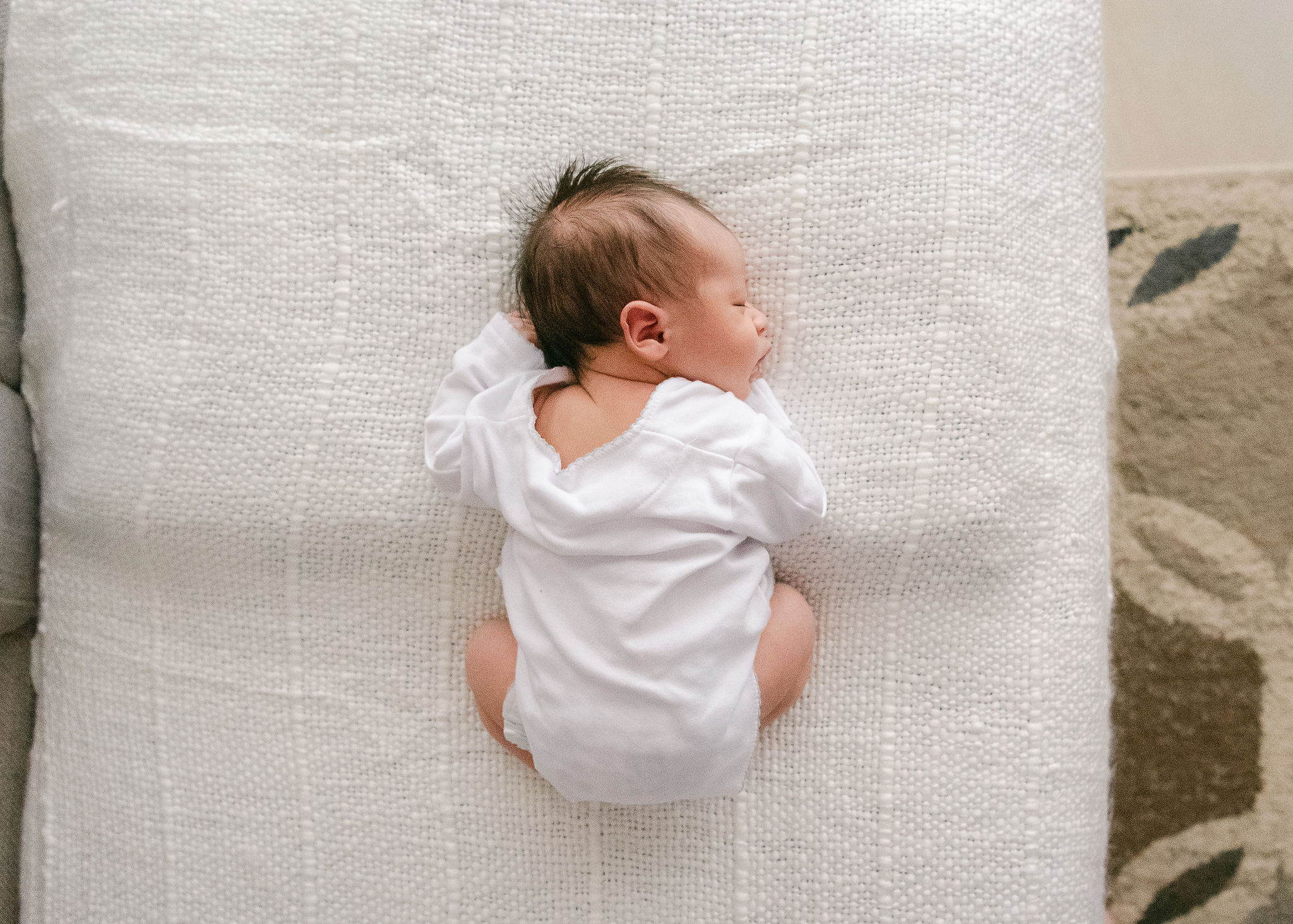 newborn baby sleeps on its stomach on a white pillow butter bug boutique