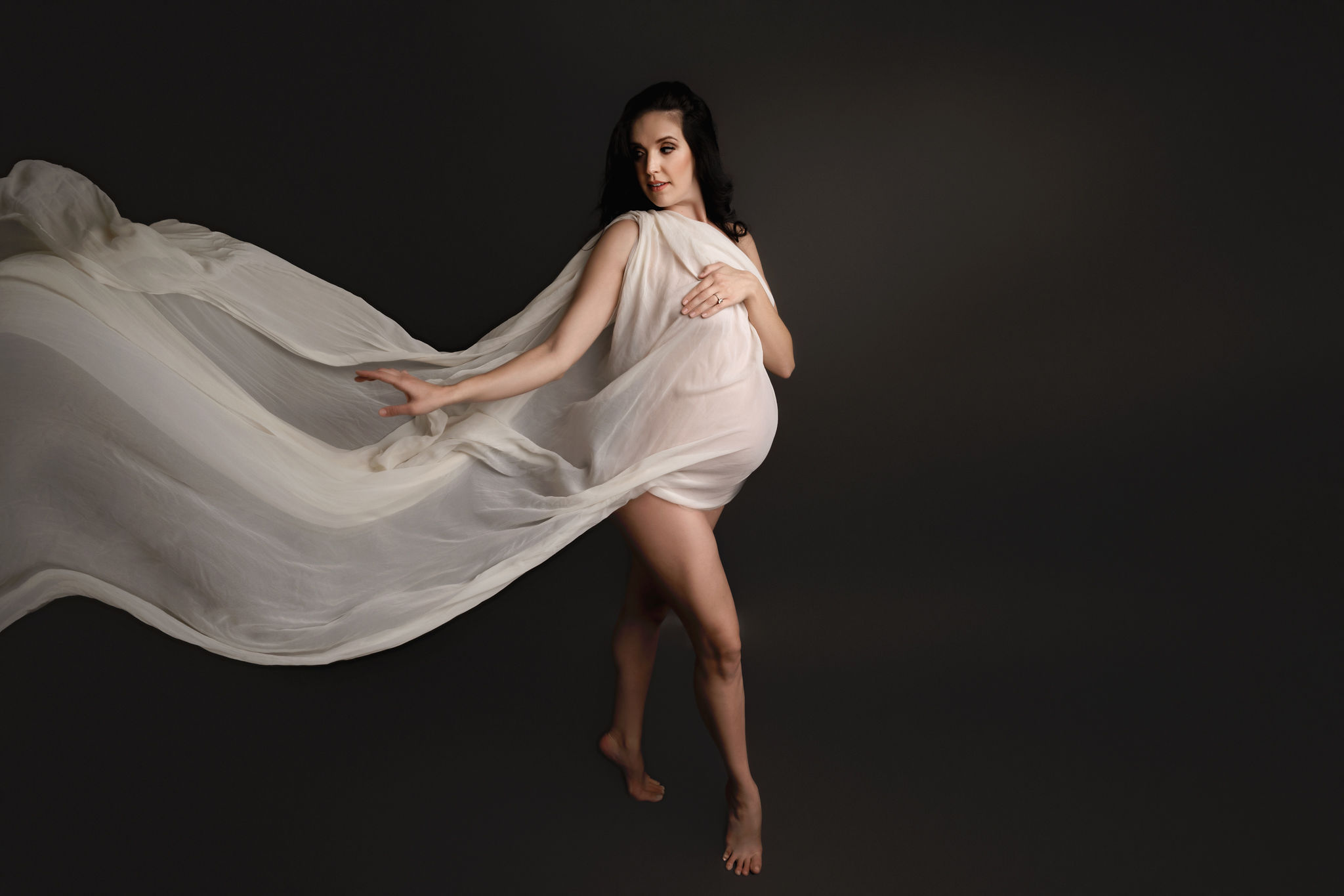 Mother to be stands in a studio with a long flowing dress tampa ultrasound