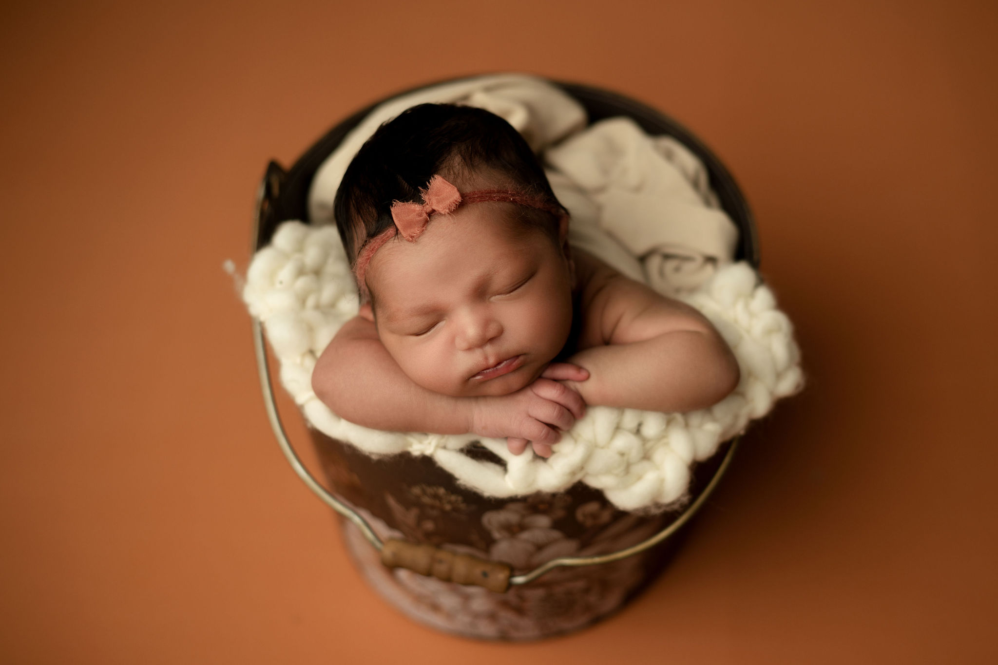 A newborn baby sleeps on its hands in a tin bucket pottery barn kids tampa